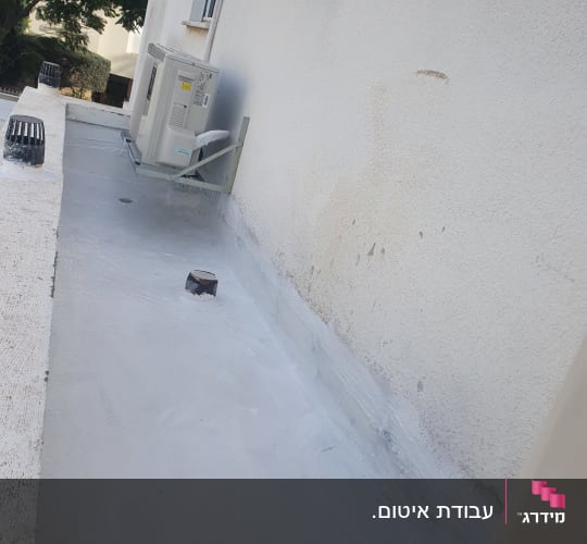 איטום גג עם חומר לבן ליד קיר חיצוני